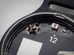 The positive battery terminal of a Misfit Shine fitness activity tracker.